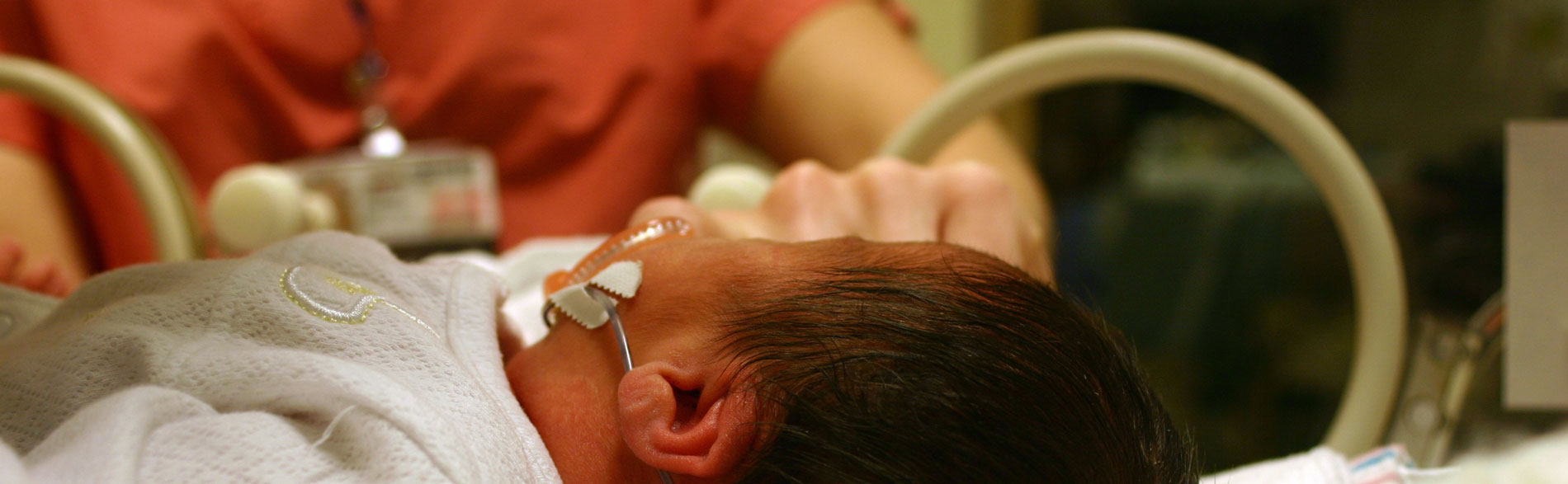 Babies with feeding tube lies on hospital bed.