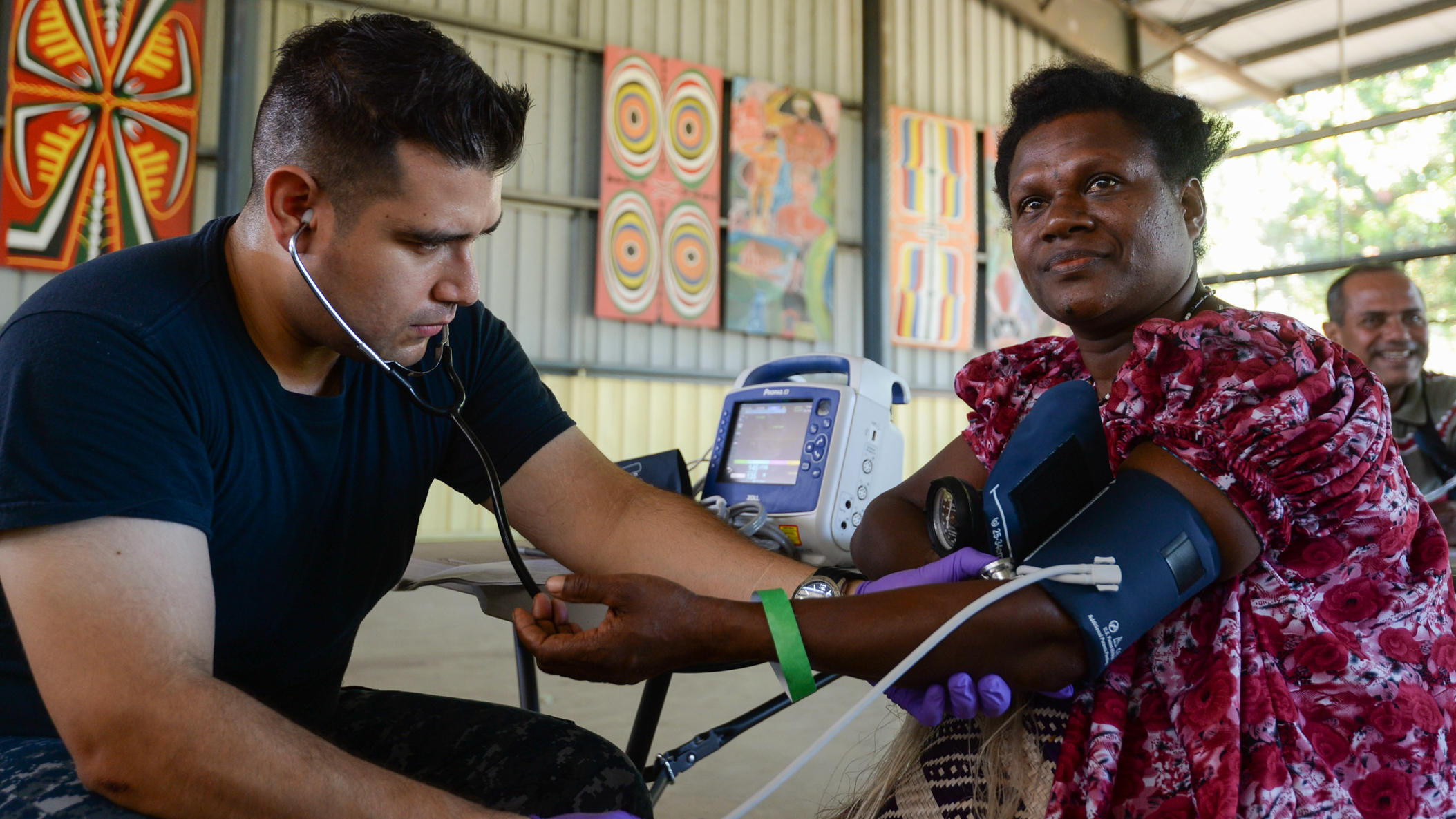Clinician taking blood pressure of a woman in a rural setting