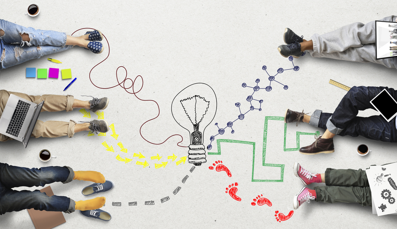 People are collaborating by sharing ideas based on their diverse forms knowledge and personal paradigms. To illustrate this concept, the image displays a hand-drawn light globe in the centre. It is surrounded by people's feet. From their feet to the light globe is a different trail for each person. Each trail is in a different colour. One trail is looping, another trail is quite angular. Each trail is different.