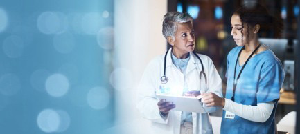 Two clinicians look at a tablet screen while discussing AI and evidence-based healthcare.