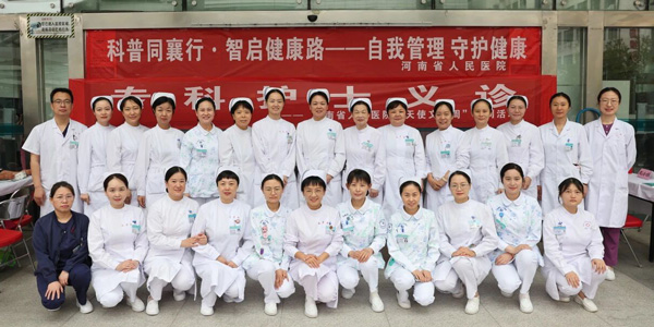 Two rows of nurses in white uniforms from the Department of Henan Provincial People’s Hospital smile in a group photo at a charity clinic