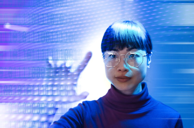 A woman touches a transparent glass screen with icons on it.