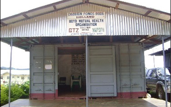A building with an aluminium roof and metal doors has a sign for Boyo Mutual Health Organisation on the front panel