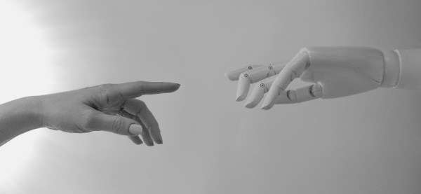 A human hand reaches towards an artificial hand to represent using AI to enhance human skill in knowledge communication