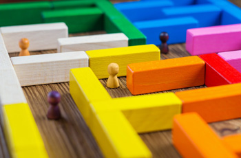 A maze made up of coloured blocks with wooden people markers representing people finding each other through collaborative knowledge communication