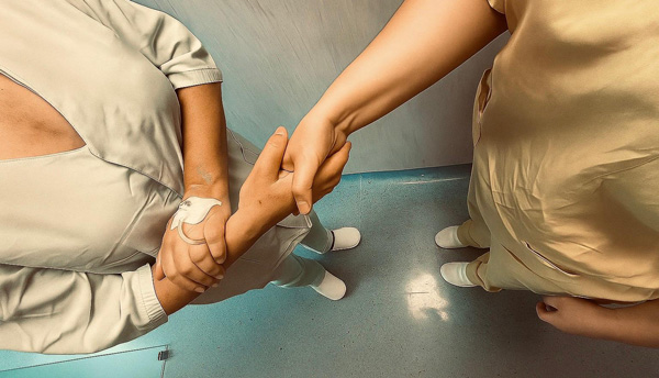 A patient and a nurse shake hands in hospital corridor
