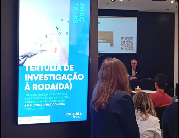 A speaker presents to an audience at an event in FNAC Coimbra